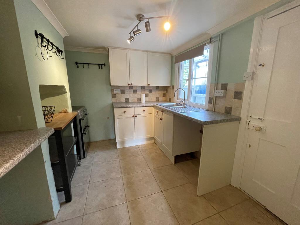 Lot: 111 - WELL PRESENTED MID-TERRACE HOUSE - Kitchen with green walls and white units